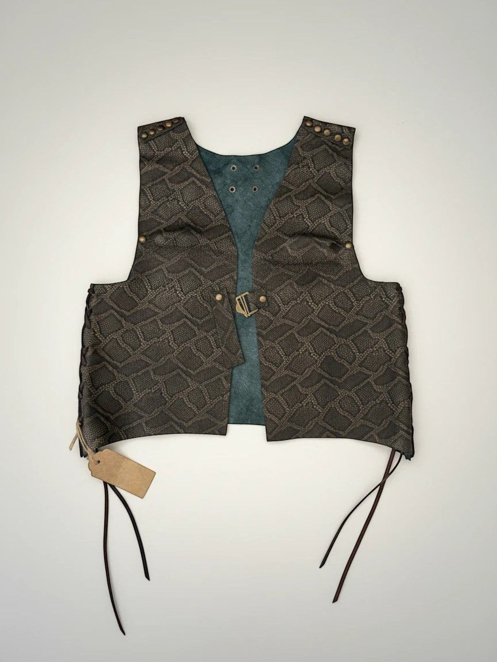 Chaleco Pampa Boho de piel con estampado de serpiente en tonos tierra y forro verde. Abertura frontal, cordones laterales y tachuelas decorativas.