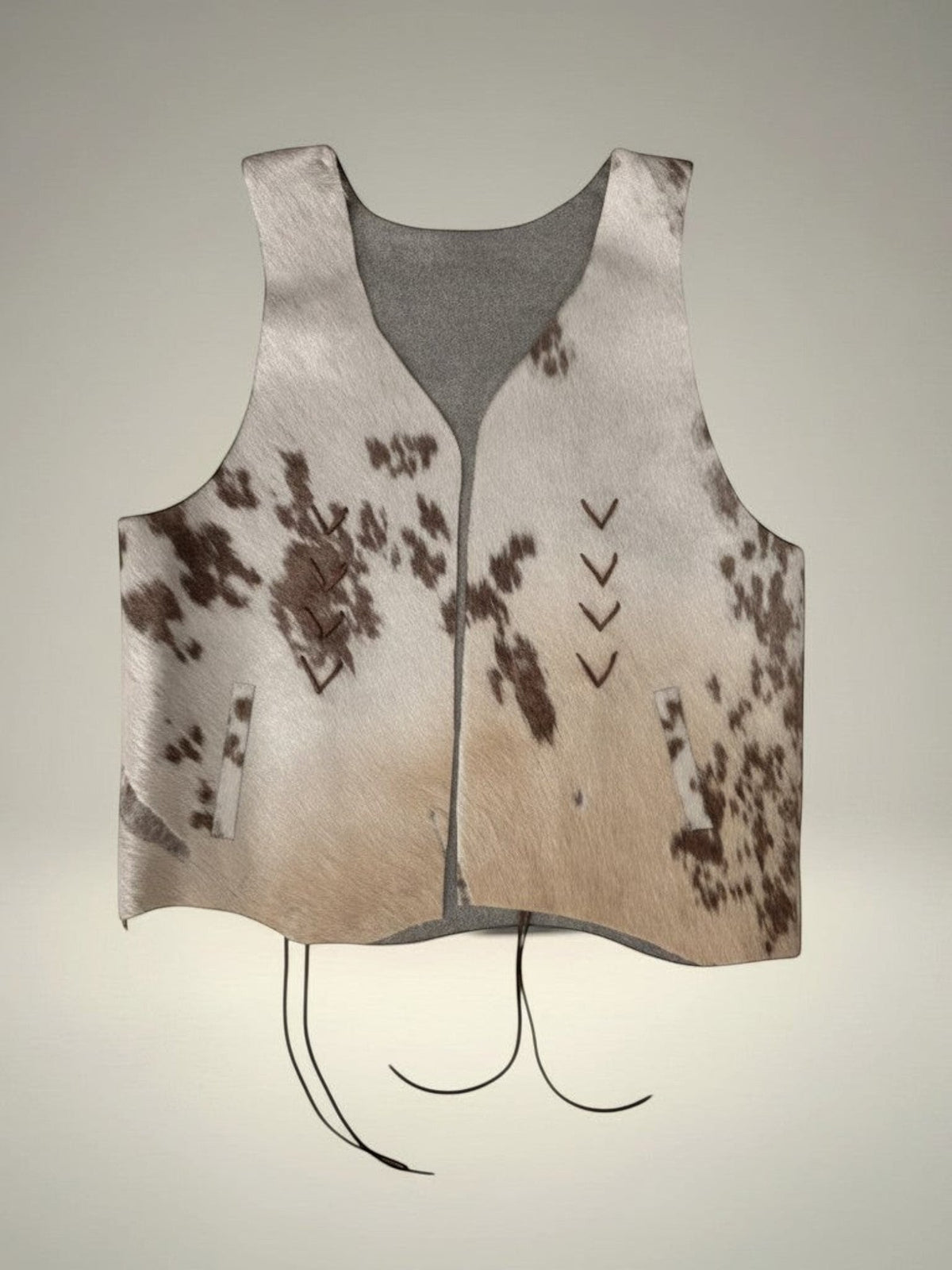 Chaleco de piel de vaca Pampa Boho con estampado moteado en blanco y marrón, tejido en los laterales y con cordones.