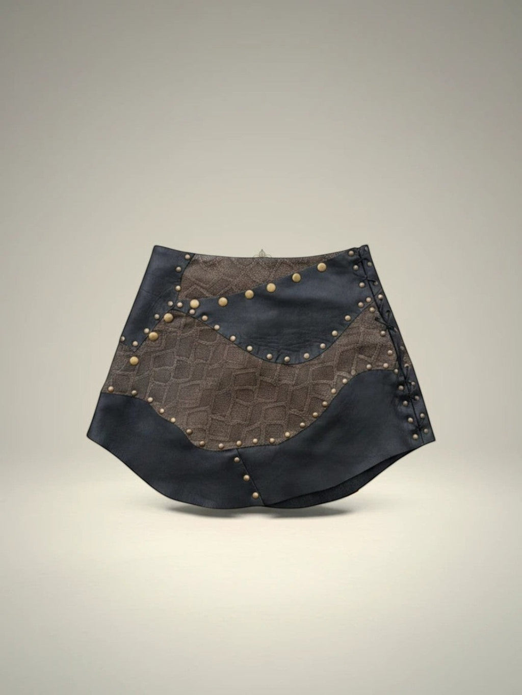 Falda corta Pampa Boho de piel negra y marrón con estoperoles y detalle de textura.